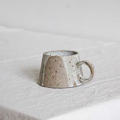 a coffee cup sitting on top of a white tablecloth covered table with no one around it