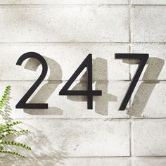 a house number sign on the side of a building with a plant in front of it