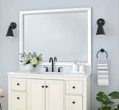 a bathroom vanity with a large mirror above it and two lights on either side of the sink