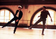 two men are dancing in an old building