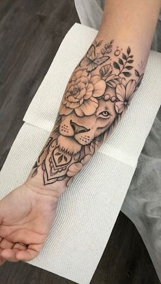 a woman's arm with flowers and a lion tattoo on the left side of her arm