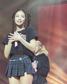 a girl standing on stage with her hands folded in front of her chest and holding a microphone