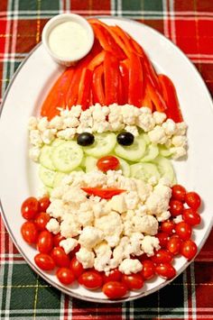 a white plate topped with cucumbers, tomatoes and cauliflower covered in cheese