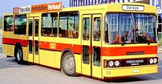 a yellow and red bus parked in front of a building