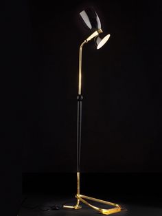 a black and gold floor lamp with two lights on it's sides, in the dark