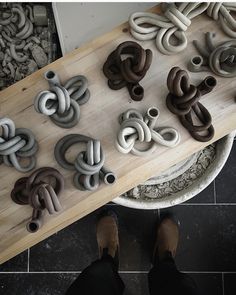 a person standing in front of a wooden table with many different types of doughnuts on it