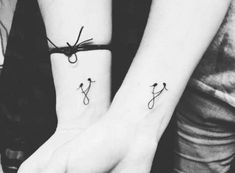 two people with matching tattoos on their wrists holding each other's hands together