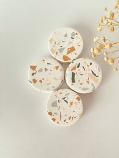 four ceramic coasters sitting on top of a table next to a vase with flowers