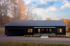 a large black house with two windows and a covered front porch in the middle of an open field