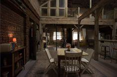 a dining table and chairs in a room with exposed brick walls, wooden beams and flooring