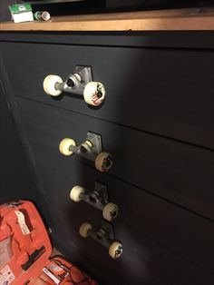 a black dresser with white knobs and two orange toolboxes on the drawers