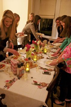 a group of people standing around a table with food on it and plates in front of them