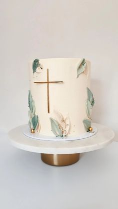 a white cake with blue leaves and a cross on top is sitting on a plate