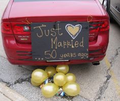 a red car with balloons and a sign that says just married 50 years ago