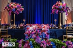 purple and blue flowers are on display at a banquet table with tall centerpieces