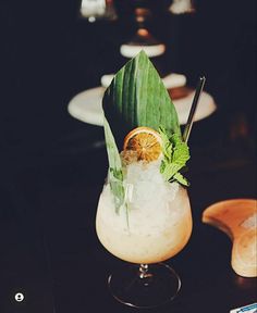 a tall glass filled with ice and topped with an orange slice