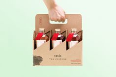 a person is holding a box with four bottles in it that are labeled teas