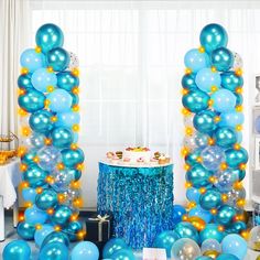 blue and gold balloons are on display in front of a table with a small cake