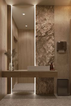 a modern bathroom with stone walls and flooring, along with a large mirror on the wall