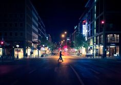 a person crossing the street at night with traffic lights on and buildings in the background