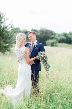 a bride and groom standing in tall grass