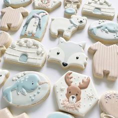 decorated cookies are arranged on a white tablecloth with blue and pink decorations, including deer, polar bear, snowman, sled