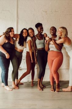 a group of women standing next to each other in front of a white brick wall