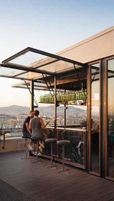 two people sitting at a bar on top of a building