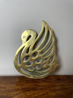 a metal swan sculpture sitting on top of a wooden table next to a white wall