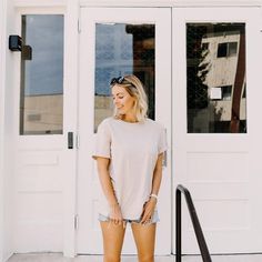 a woman standing in front of a white door wearing shorts and a t - shirt