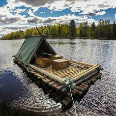 there is a boat made out of logs in the water with a tarp on top