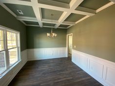 an empty living room with wood floors and white trim on the ceiling, painted green