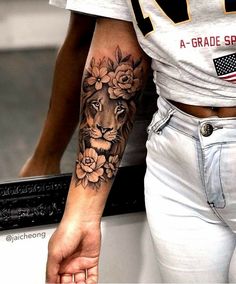 a woman's arm with a lion and flowers tattoo on her left arm, next to a mirror