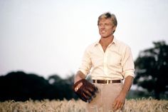 a man standing in a field with his hands on his hip and wearing a glove