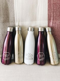 four different colored stainless steel water bottles lined up in a row on top of a couch