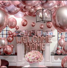 a welcome home sign surrounded by pink and white flowers in front of balloons that spell out the word welcome home