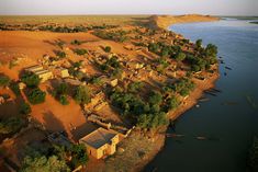 an aerial view of a small village on the edge of a body of water, surrounded by trees and sand dunes