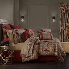 a bed with red and gold comforters in a bedroom next to a window covered by curtains