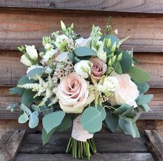 a bouquet of flowers sitting on top of a wooden box next to a wall with wood planks