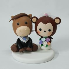 a bride and groom figurine sitting next to each other on a white surface