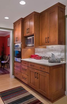 a kitchen with wooden cabinets and white counter tops next to a dining room table in front of an open door