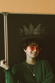 a young man wearing a hat and holding a stick in front of his face with red paint on it