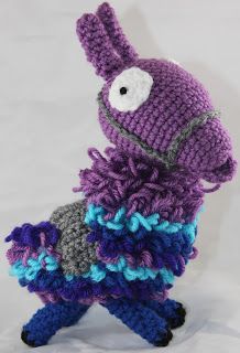 a crocheted purple and blue stuffed animal sitting on top of a white surface