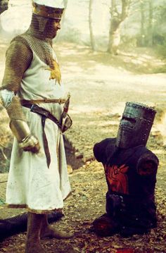 a man dressed as a knight standing next to a fire hydrant in the woods