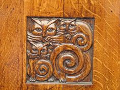 carved wood panel with cats and spirals on it's face in the center