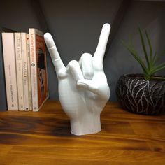 a white hand statue sitting on top of a wooden table next to a potted plant