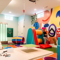 a child is playing in an indoor play area with colorful furniture and artwork on the walls