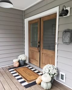 the front door is decorated with pumpkins and flowers