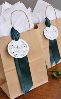 two brown paper bags with green ribbons and tags on them sitting on a wooden table