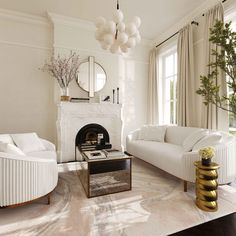 a living room filled with white furniture and a fire place in front of a window